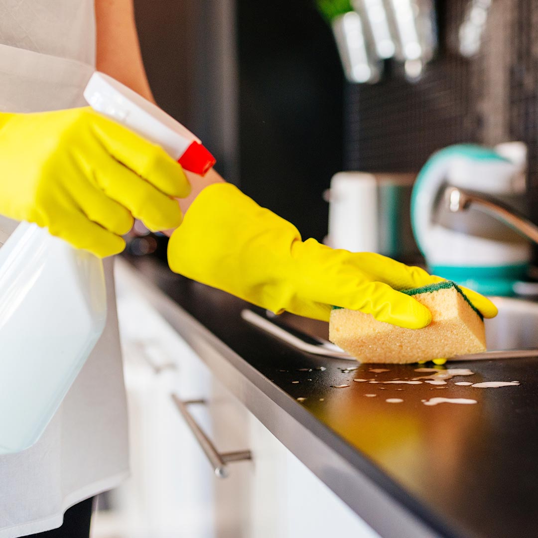 Woman wearing yellow gloves cleaning a kitchen counter